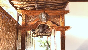 A corridor with a thatched roof, wooden columns, and intricate carvings.