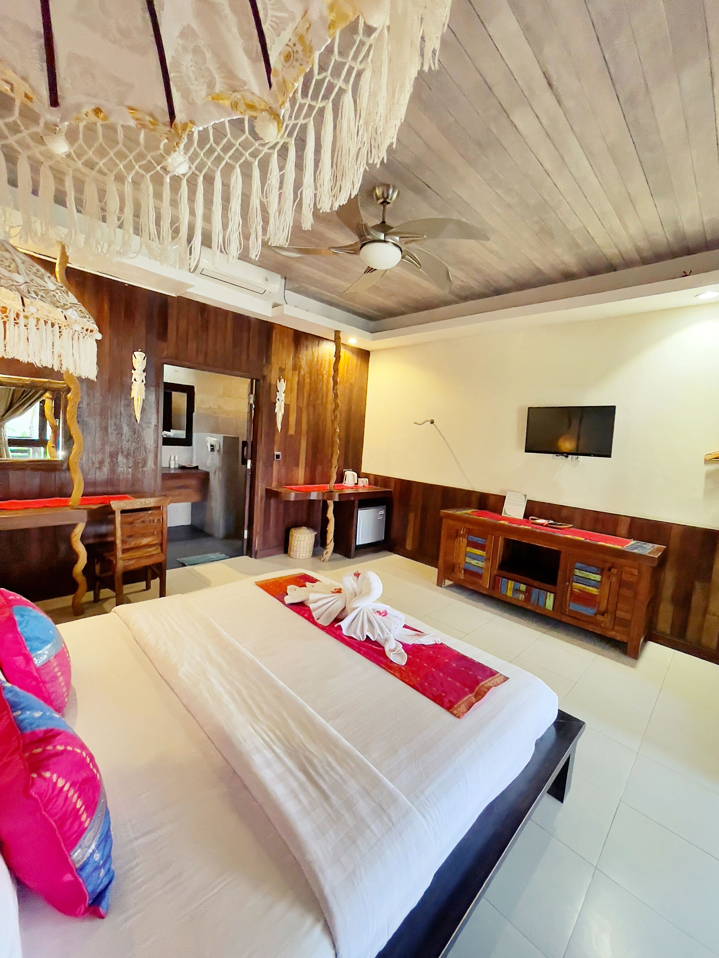 A hotel room with a bed, a desk, a television, and a minibar.