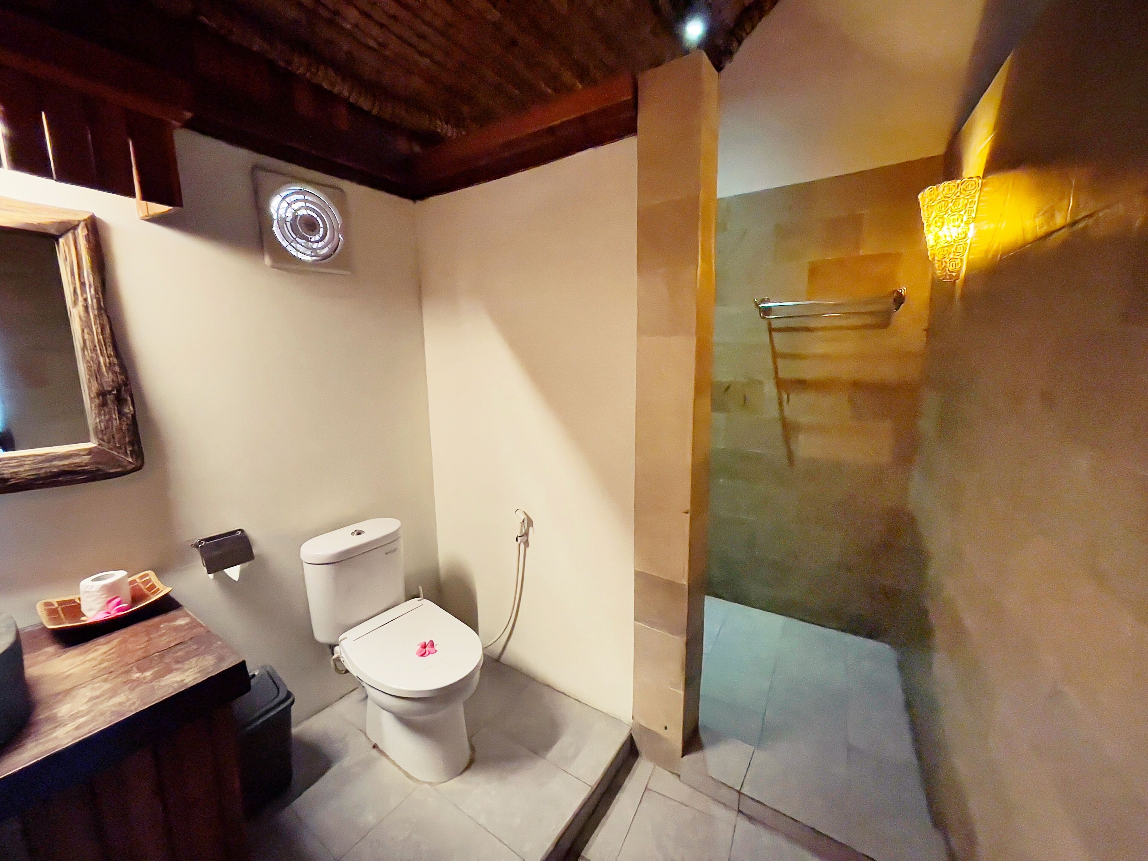 Ein Badezimmer mit Toilette, Waschbecken, Spiegel und Duschbereich.