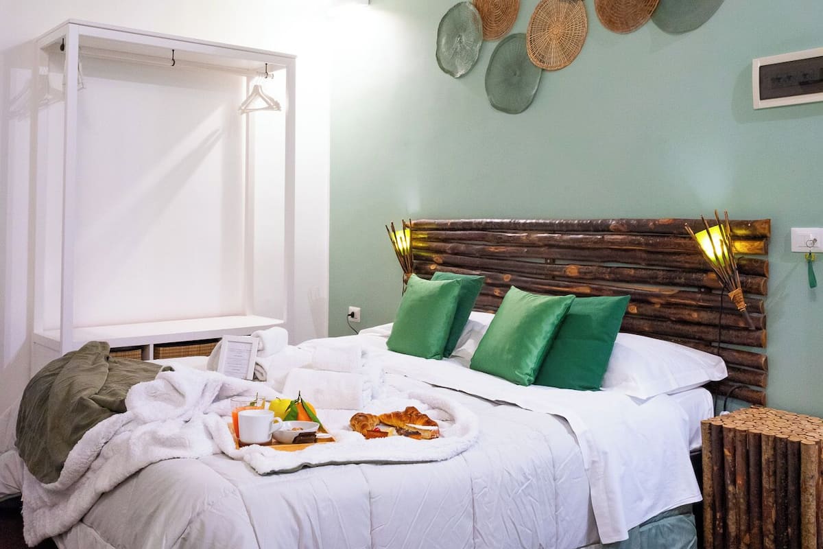 Un dormitorio con una cama, una mesita de noche, una lámpara colgante y un estante en la pared.