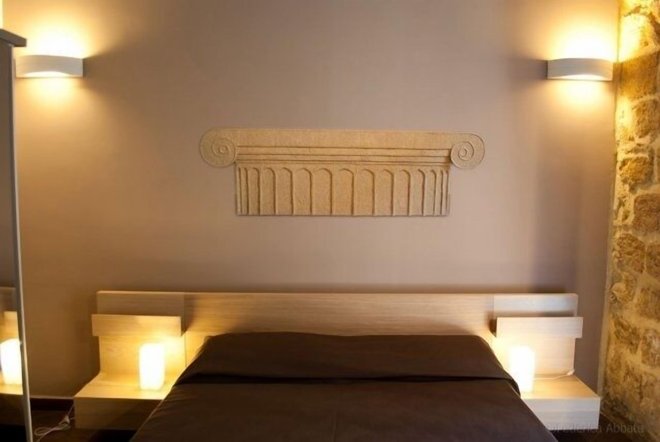 A bedroom with a headboard, bedside lamps, and a bed with a dark-colored bedspread.