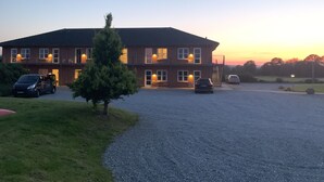 A two-story building with a gravel driveway and parked cars. - Hotel Korning B&B  (Horsens)