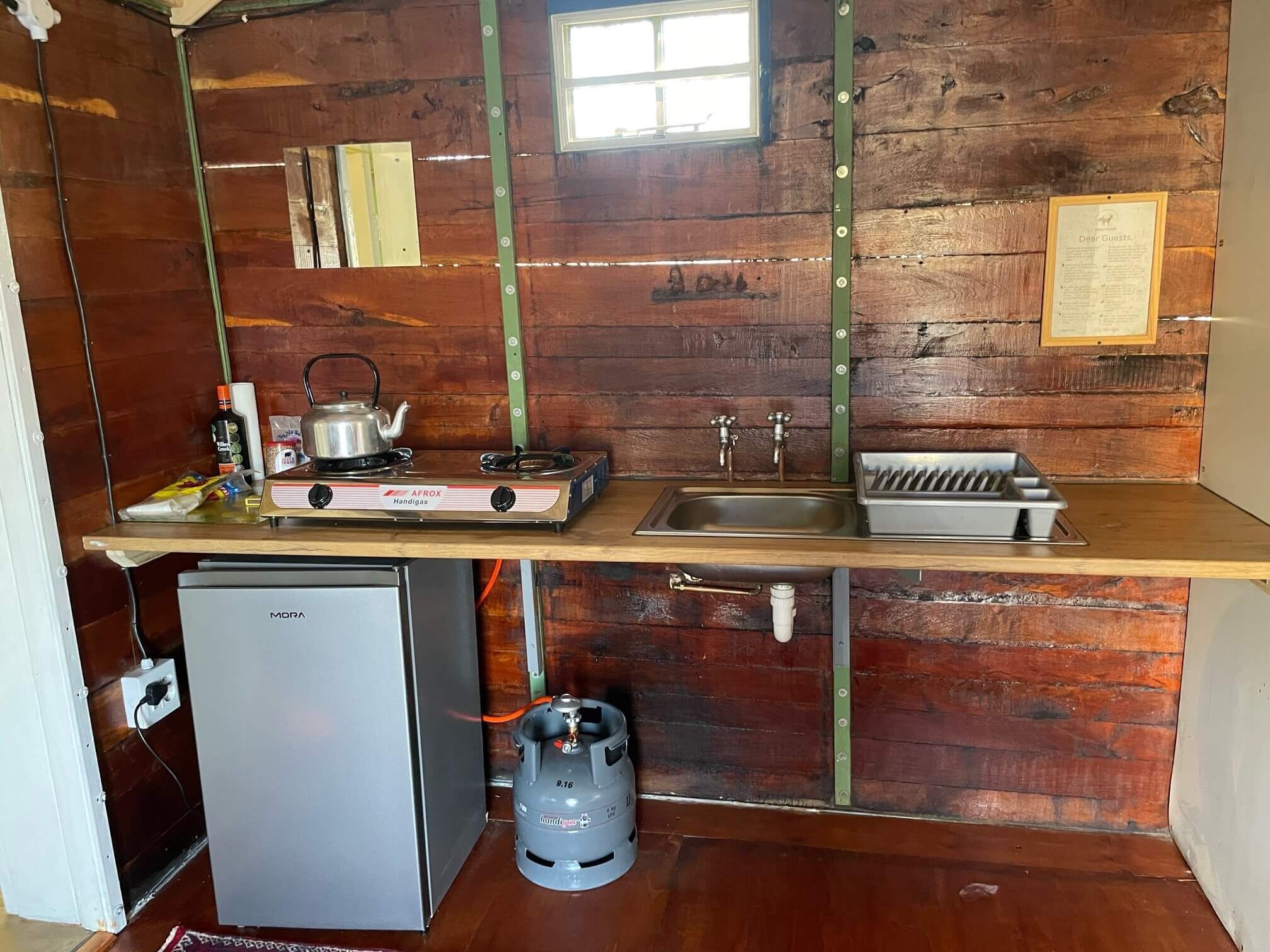 A compact kitchen with a gas stove, sink, and a small refrigerator.