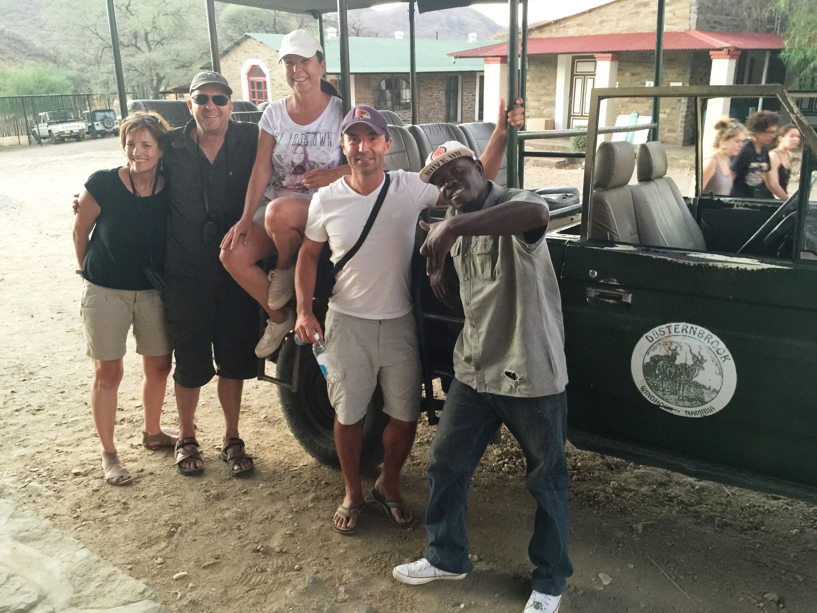 Eine Gruppe von Personen posiert mit einem grünen Fahrzeug, auf dem ein Aufkleber mit der Aufschrift "DUISTERNBROOK Namibia" zu sehen ist.