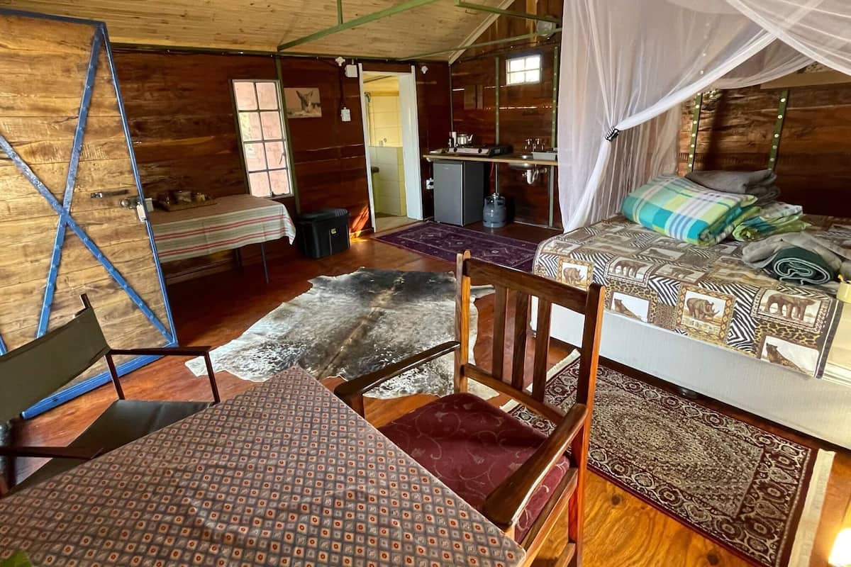 A rustic wooden cabin with a bed, a desk, and a chair.