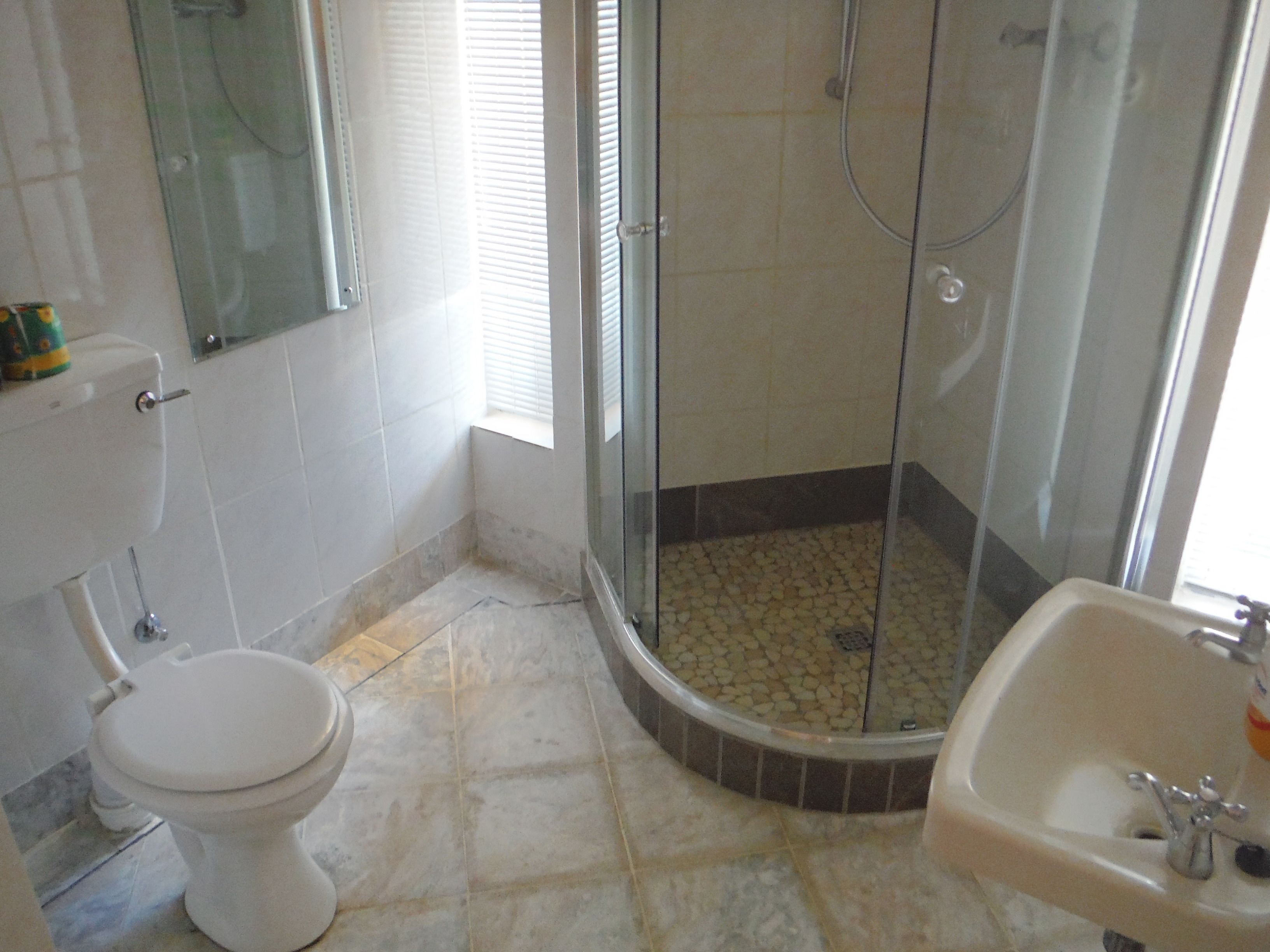 A bathroom with a toilet, a shower with a glass door, and a sink.