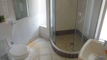 A bathroom with a toilet, a shower with a glass door, and a sink.
