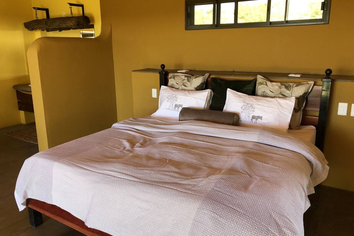 A bed with a patterned bedspread, a wooden headboard, and decorative pillows.