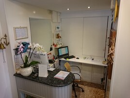 A small office with a desk, computer, chair, and various office supplies.