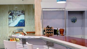 Un área de bar moderna con una barra curva, taburetes azules y lámparas colgantes azules.