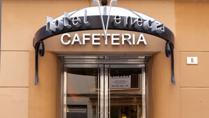 La entrada a una cafetería con puerta de cristal y un letrero encima.
