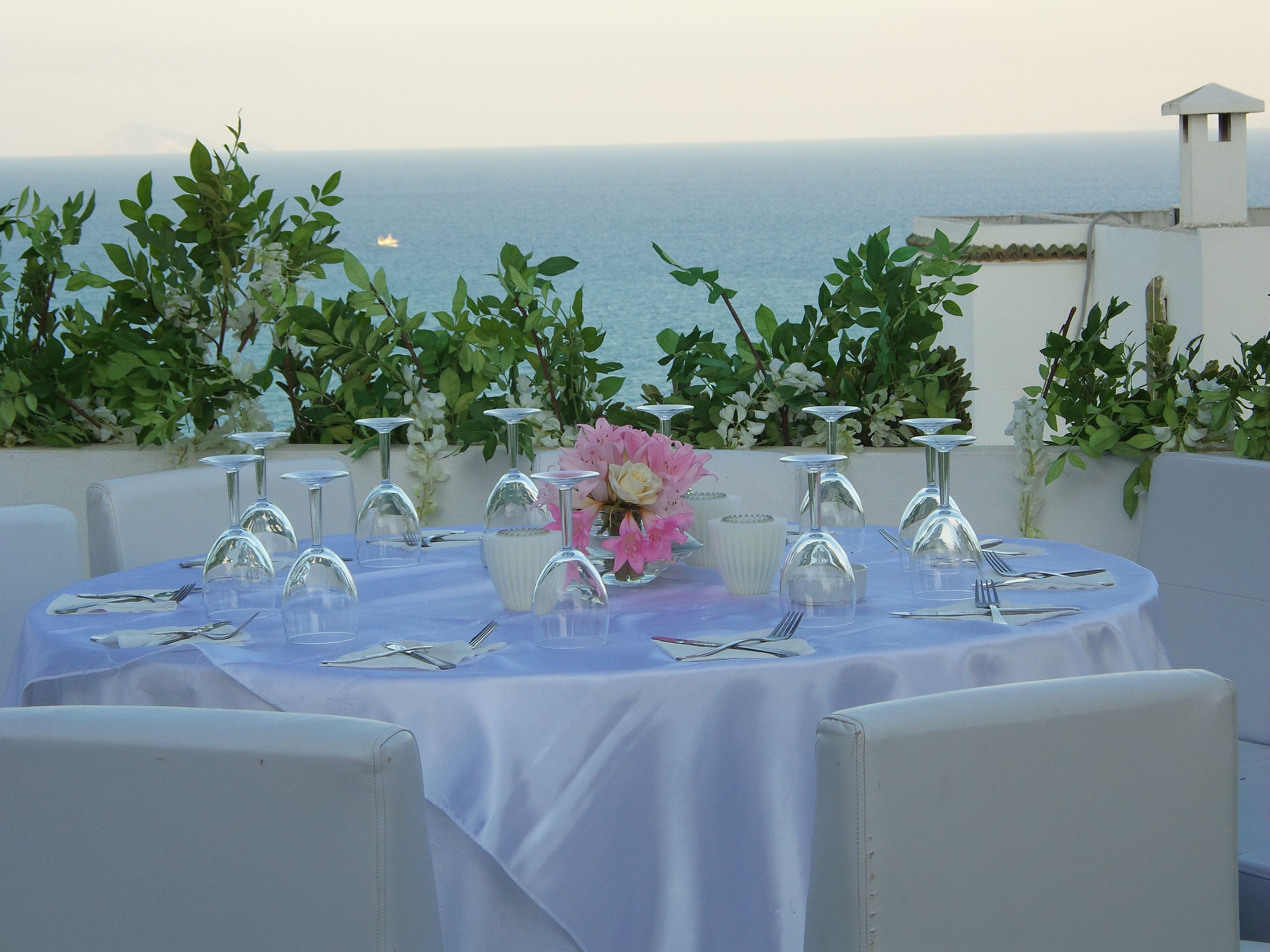 A round table set for a meal with a view of the sea.