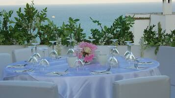 A round table set for a meal with a view of the sea.