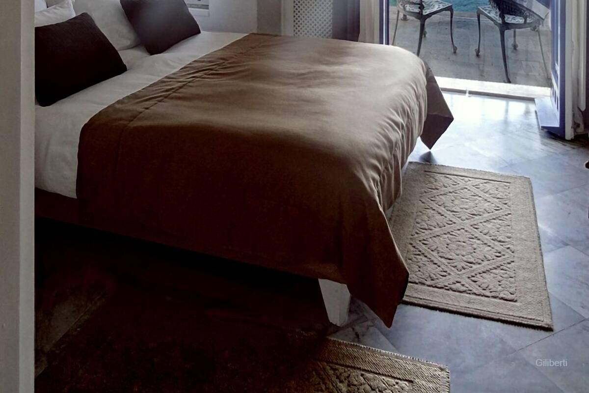 A bedroom with a large bed, a view of a pool, and a balcony.