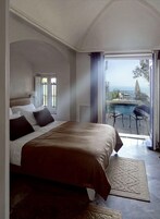 Un dormitorio con una cama grande, vistas a una piscina y un balcón.