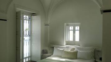 Quarto com cama grande, janela e porta com vista para o exterior.