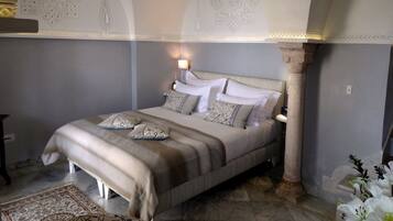 A bedroom with a large bed, a nightstand, a lamp, and a decorative wall pattern.