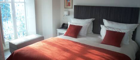 Habitación de hotel con una cama grande, dos almohadas, una mesita de noche con teléfono y una ventana con vistas.