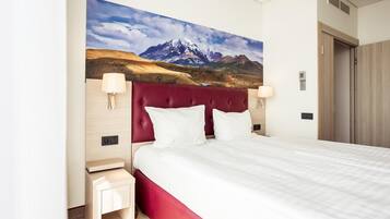 Habitación de hotel con una cama grande, cabecera roja y un cuadro de un paisaje de montaña en la pared.