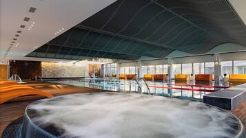 Ein moderner Innenpool mit Whirlpool, Holzboden und einem großen Fenster mit Blick zum Himmel.