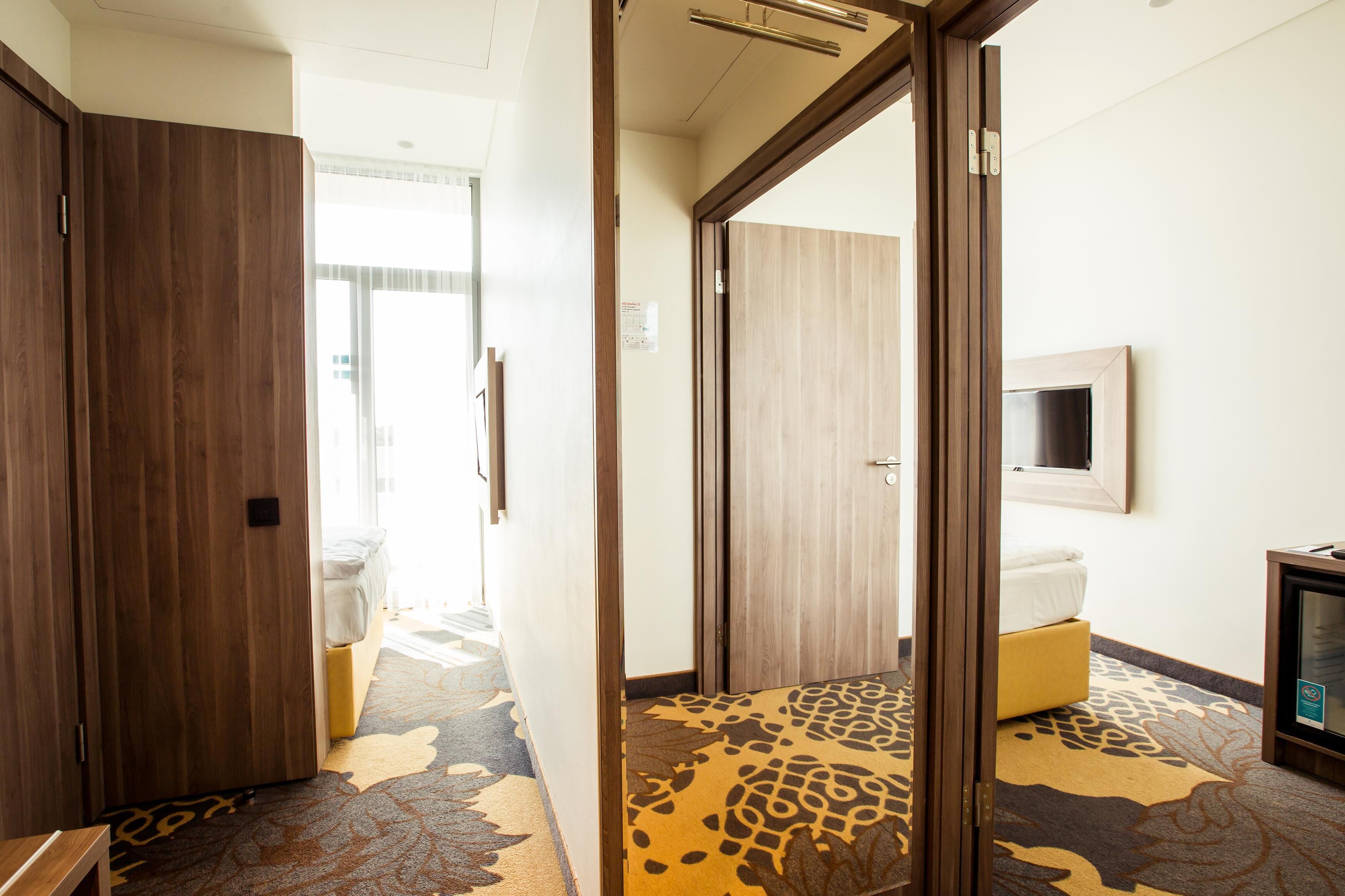 Una habitación de hotel con cama, televisión y armario de madera.
