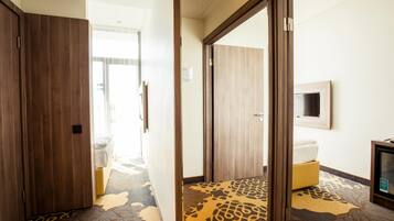 A hotel room with a bed, a TV, and a wooden wardrobe.