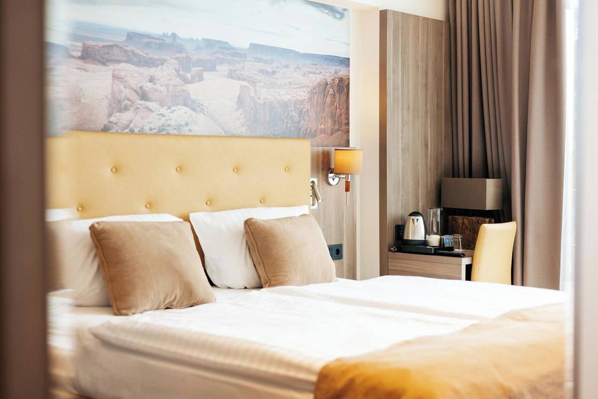 Ein Hotelzimmer mit einem großen Bett, einem Nachttisch mit Lampe und Blick auf eine Schlucht.