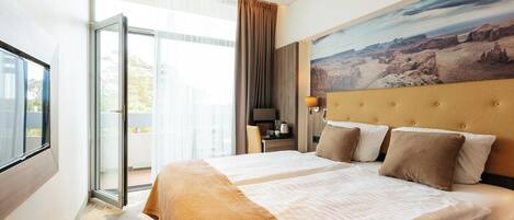 Camera d'albergo con un letto grande, una scrivania, una sedia, una finestra e un quadro appeso al muro.
