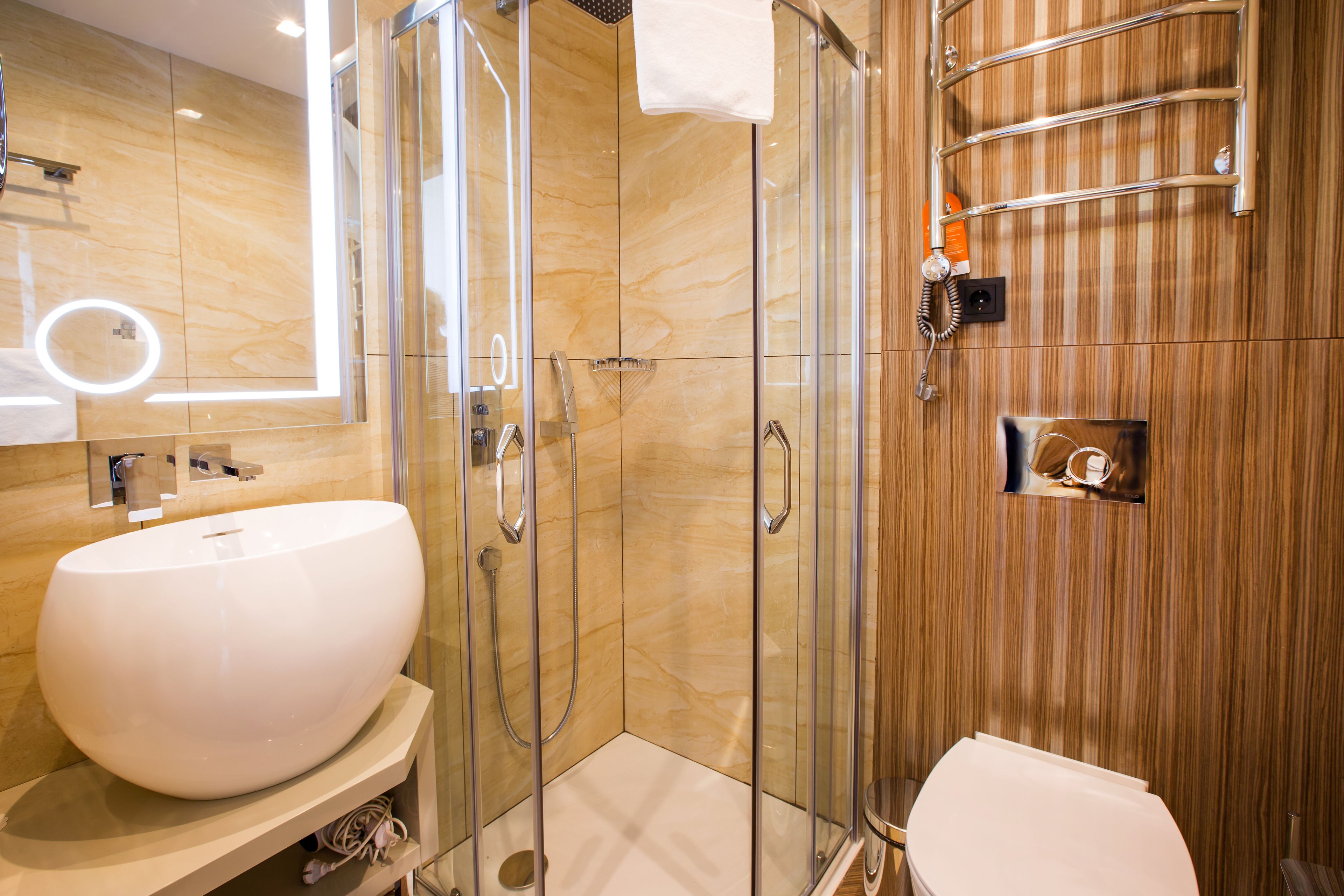 A modern bathroom with a large white sink, a glass-enclosed shower, and a wooden vanity.