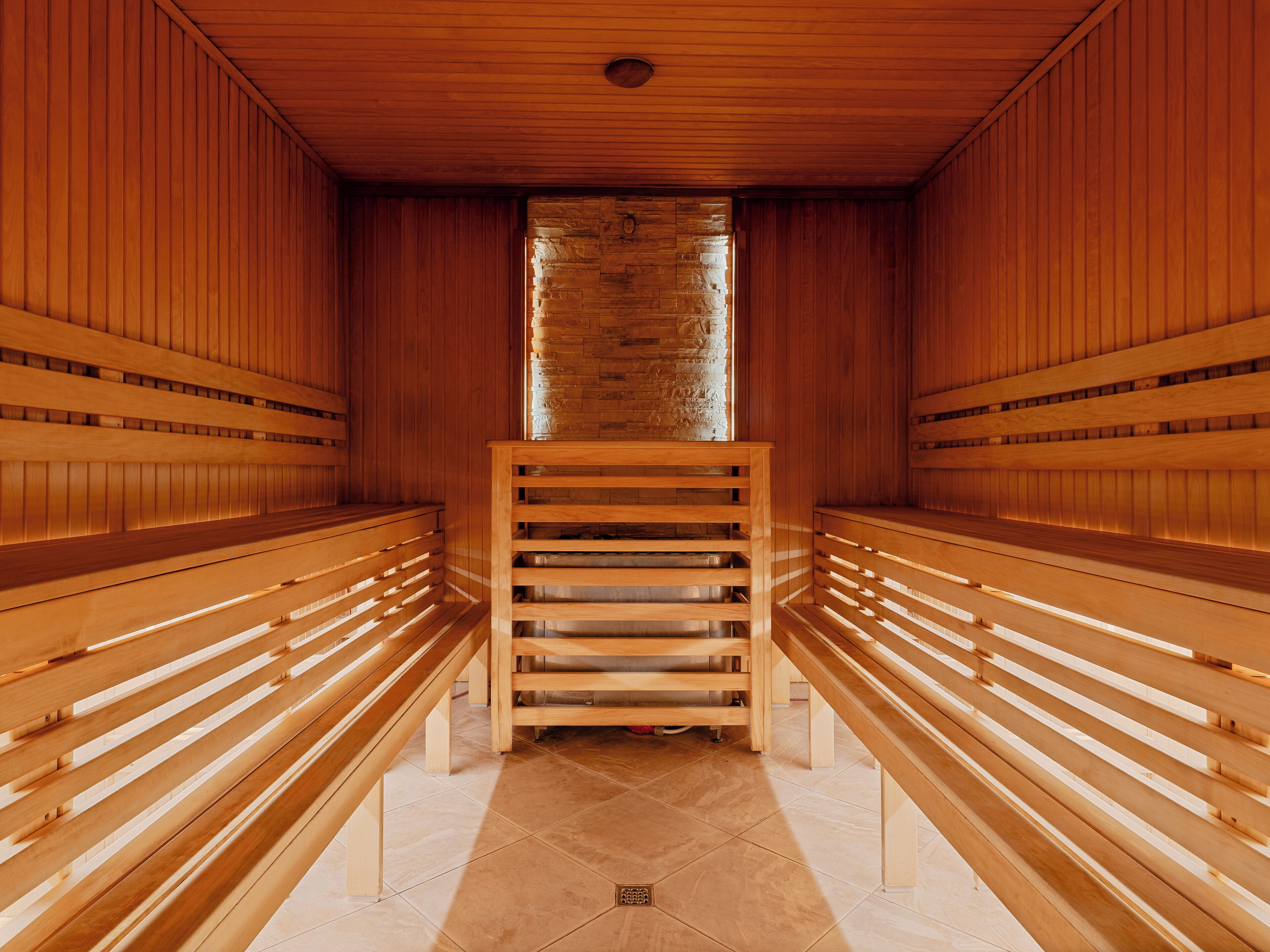 A sauna with wooden benches and a stone wall.