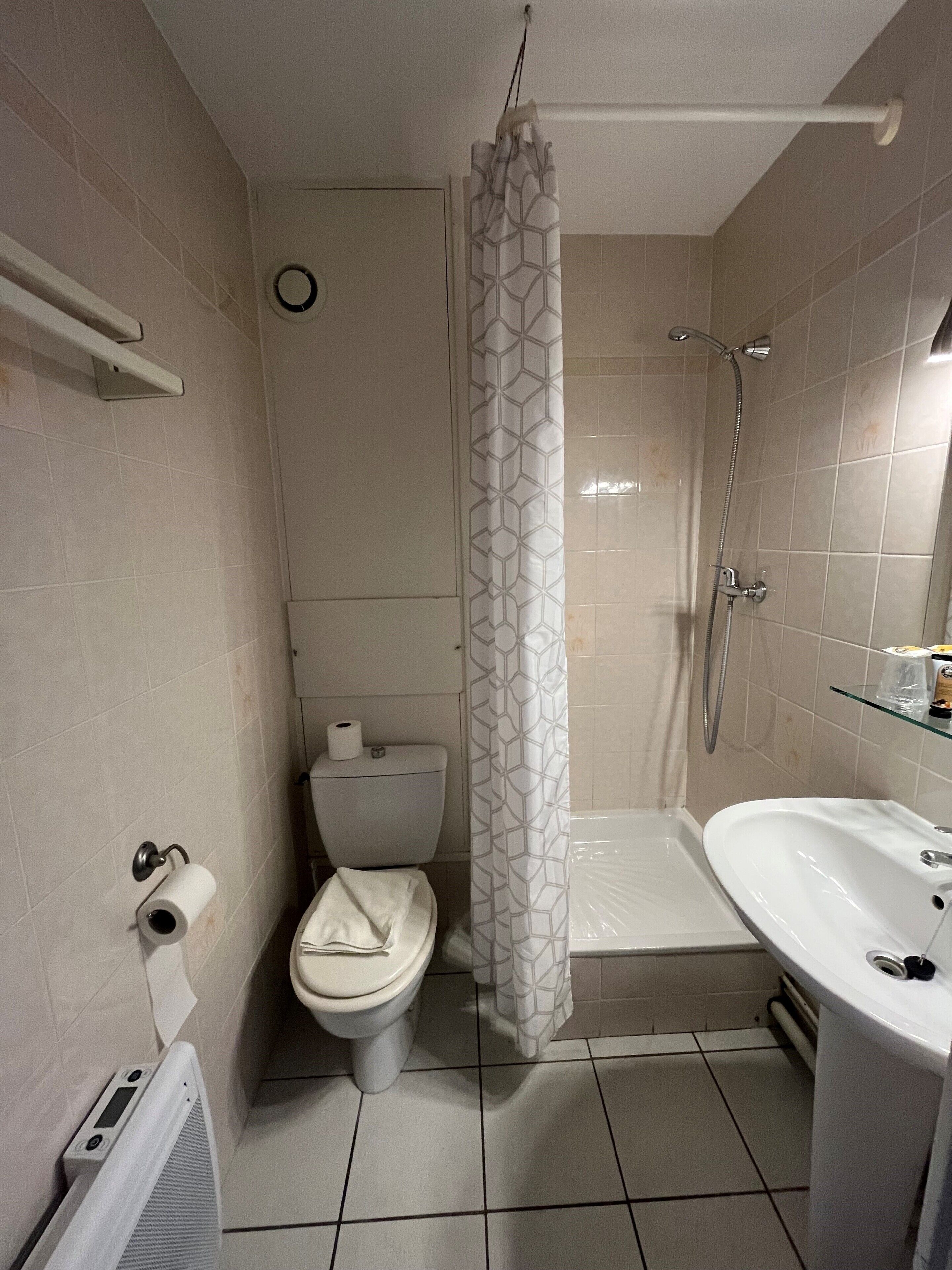 A bathroom with a toilet, shower, and sink.