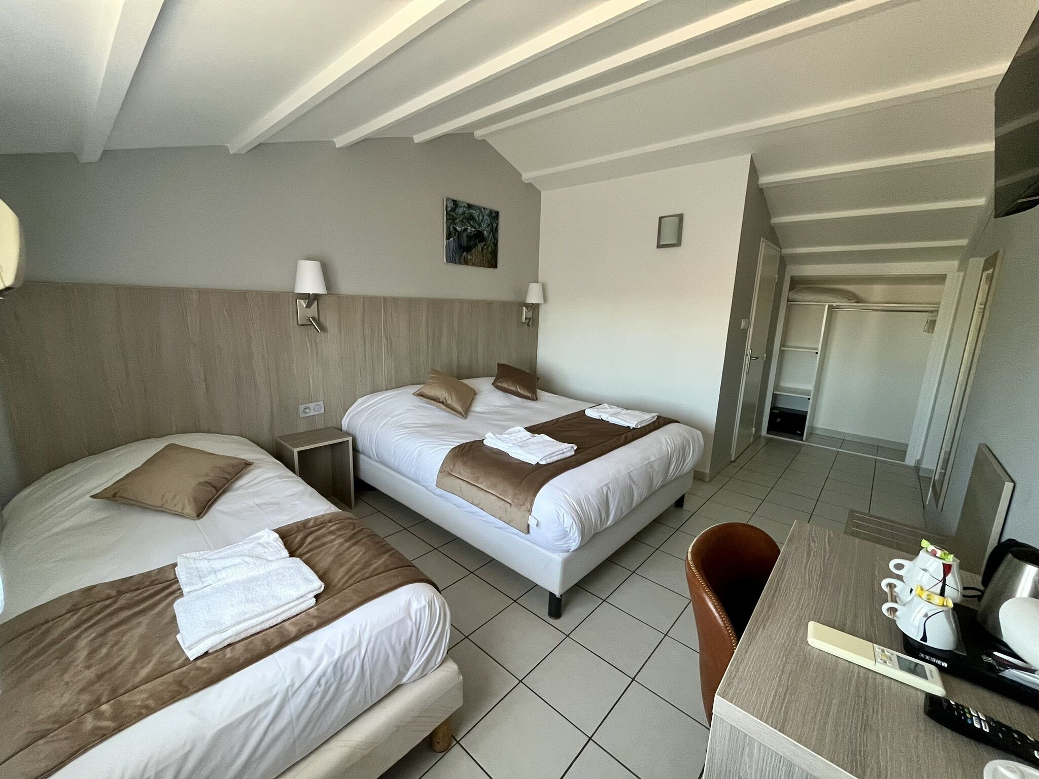 A hotel room with two beds, a desk, and a chair.