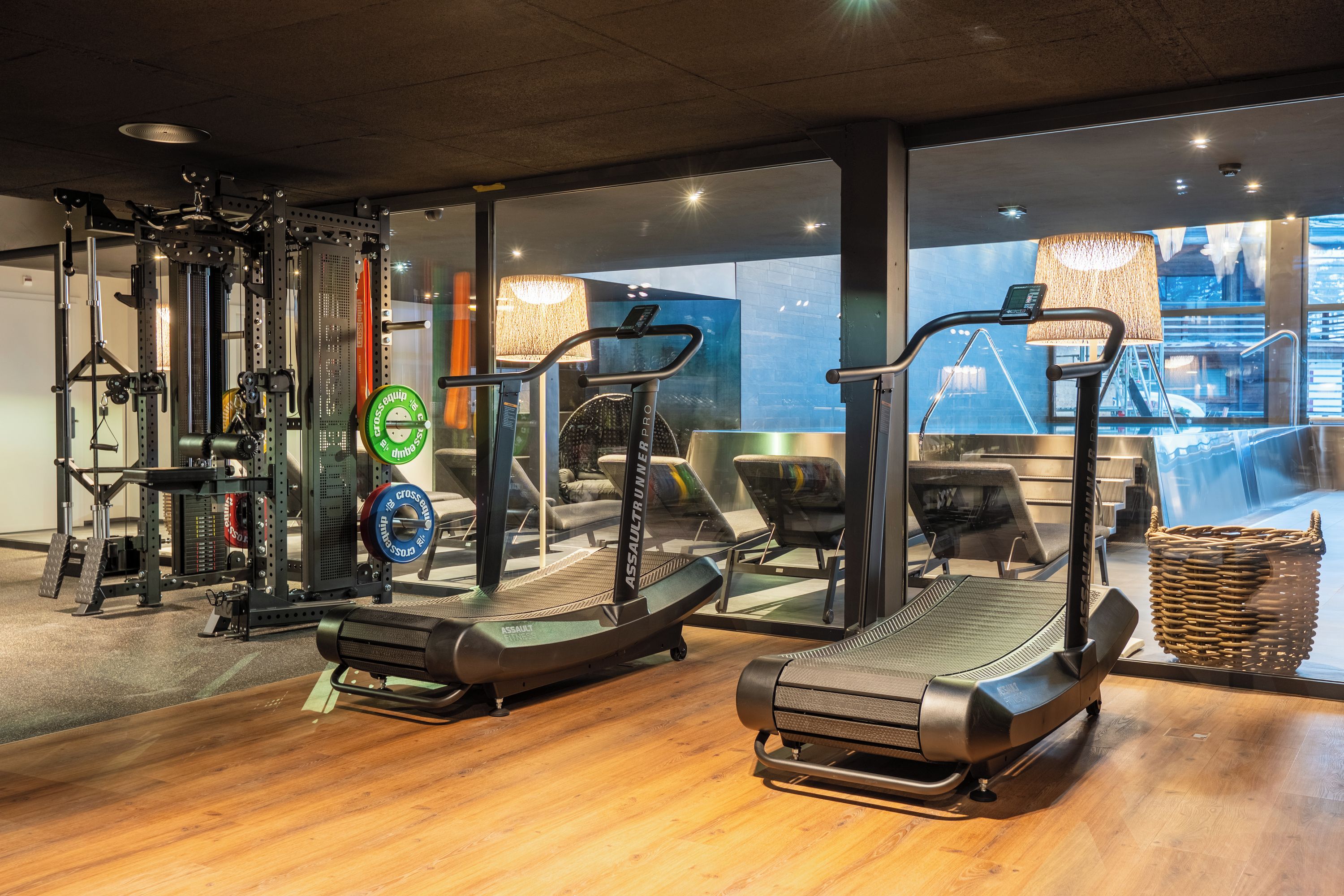 Een sportschool met loopbanden, krachttrainingsapparaten en een spiegelwand.