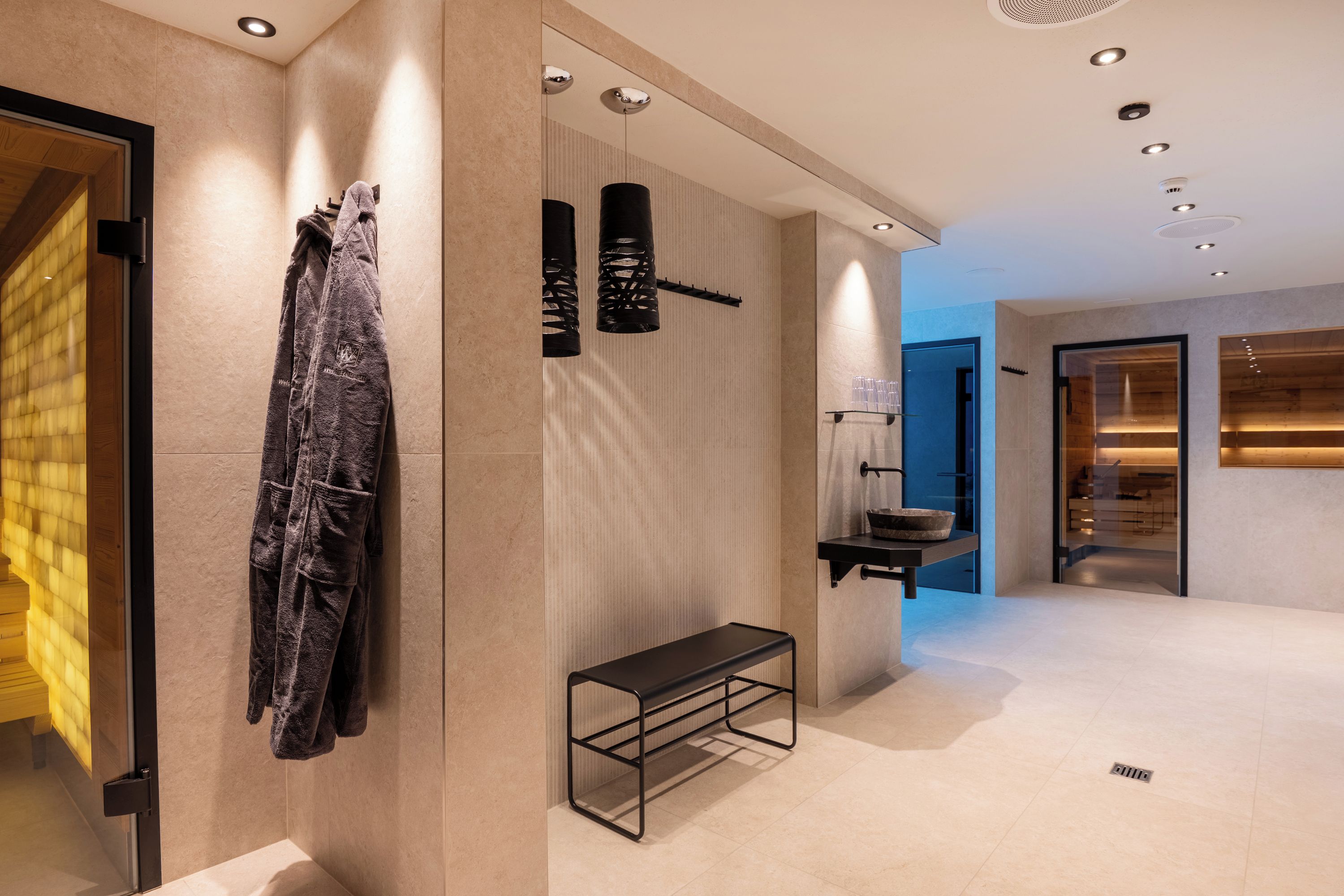 Un baño moderno con banco, perchero para toallas y cabina de ducha de vidrio.