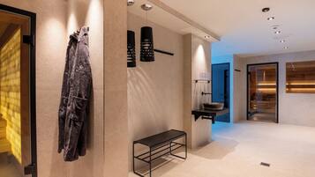 Une salle de bain moderne avec un banc, un porte-serviettes et une douche en verre.