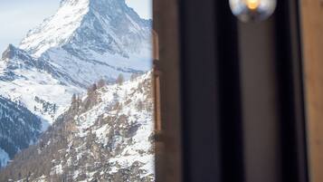 Blick auf Berge durch ein Fenster mit hängenden Lampen.