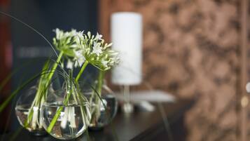 Trois vases en verre contenant de l’eau et des plantes vertes, posés sur une surface sombre.