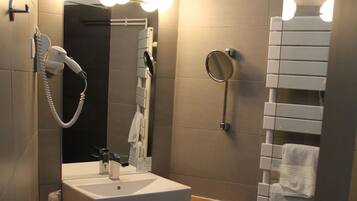 A modern bathroom with a white sink, a hairdryer, a mirror, and a towel rack.