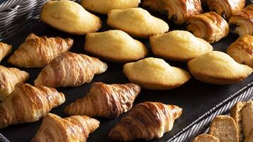 A variety of pastries, including croissants and bread rolls, arranged on a dark surface.