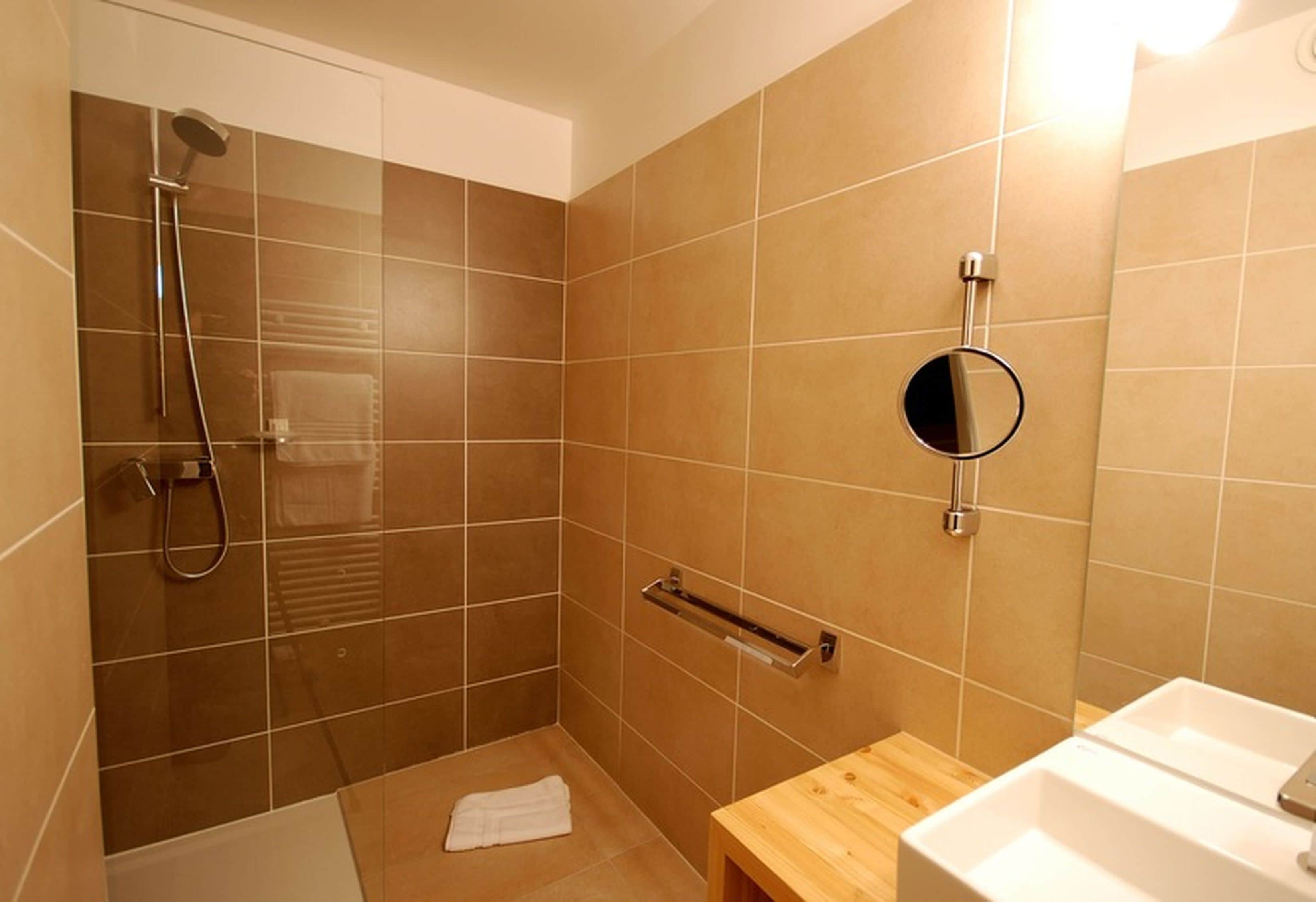 Un bagno con doccia, lavandino e specchio.