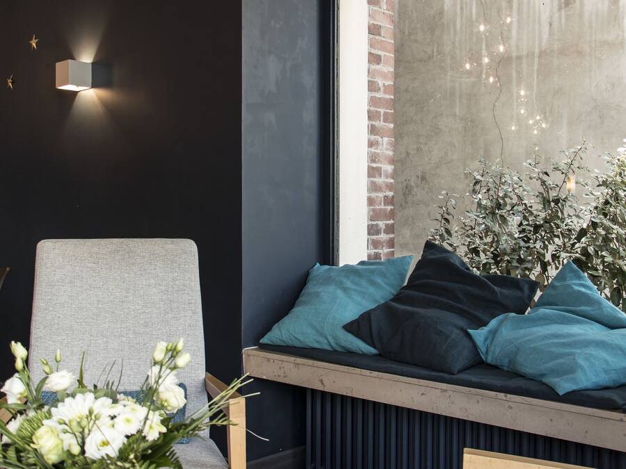 A modern living room with a grey sofa, a wooden chair, a black coffee table, and a vase of white flowers.