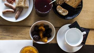 A breakfast table with various food items, including bread, sausages, and a croissant.