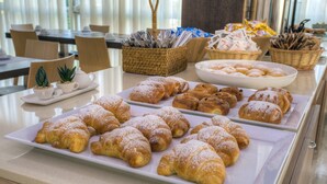 Une table de buffet garnie de diverses pâtisseries et un panier en osier contenant des ustensiles.
