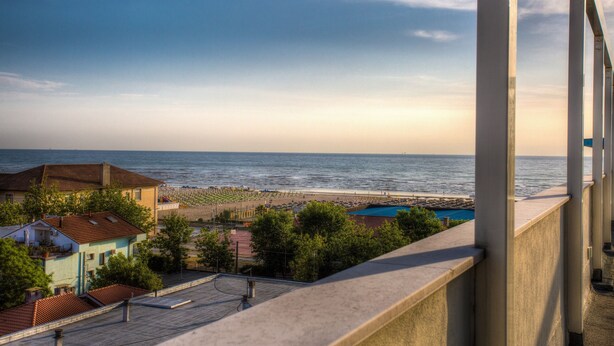 Un balcon donnant sur une plage, avec un ciel dégagé.