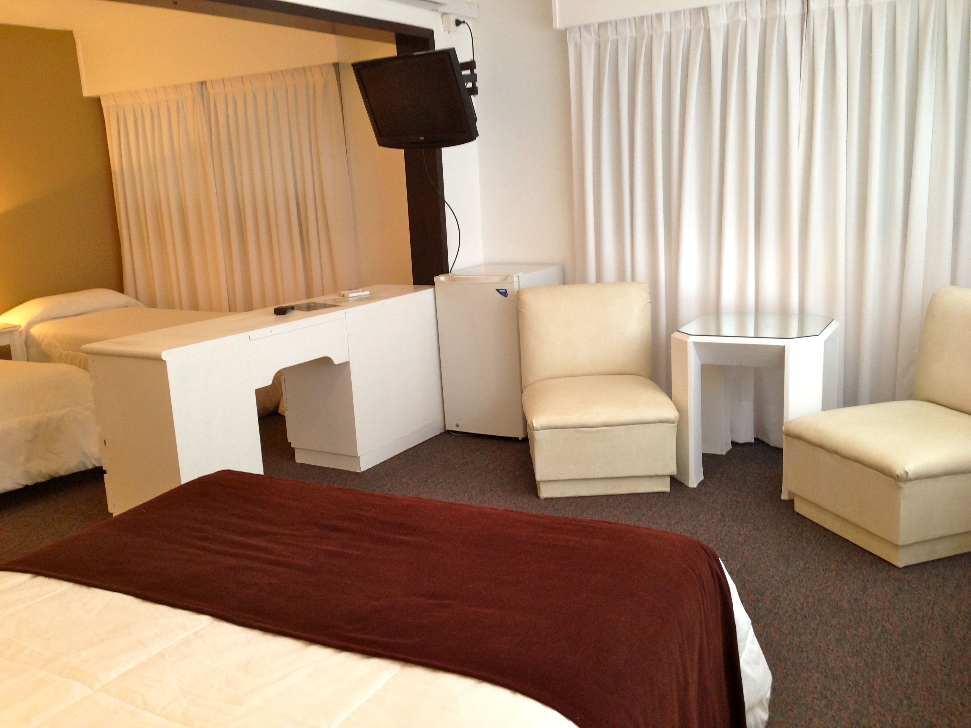 Habitación de hotel con cama, escritorio, silla, mesita y televisión.