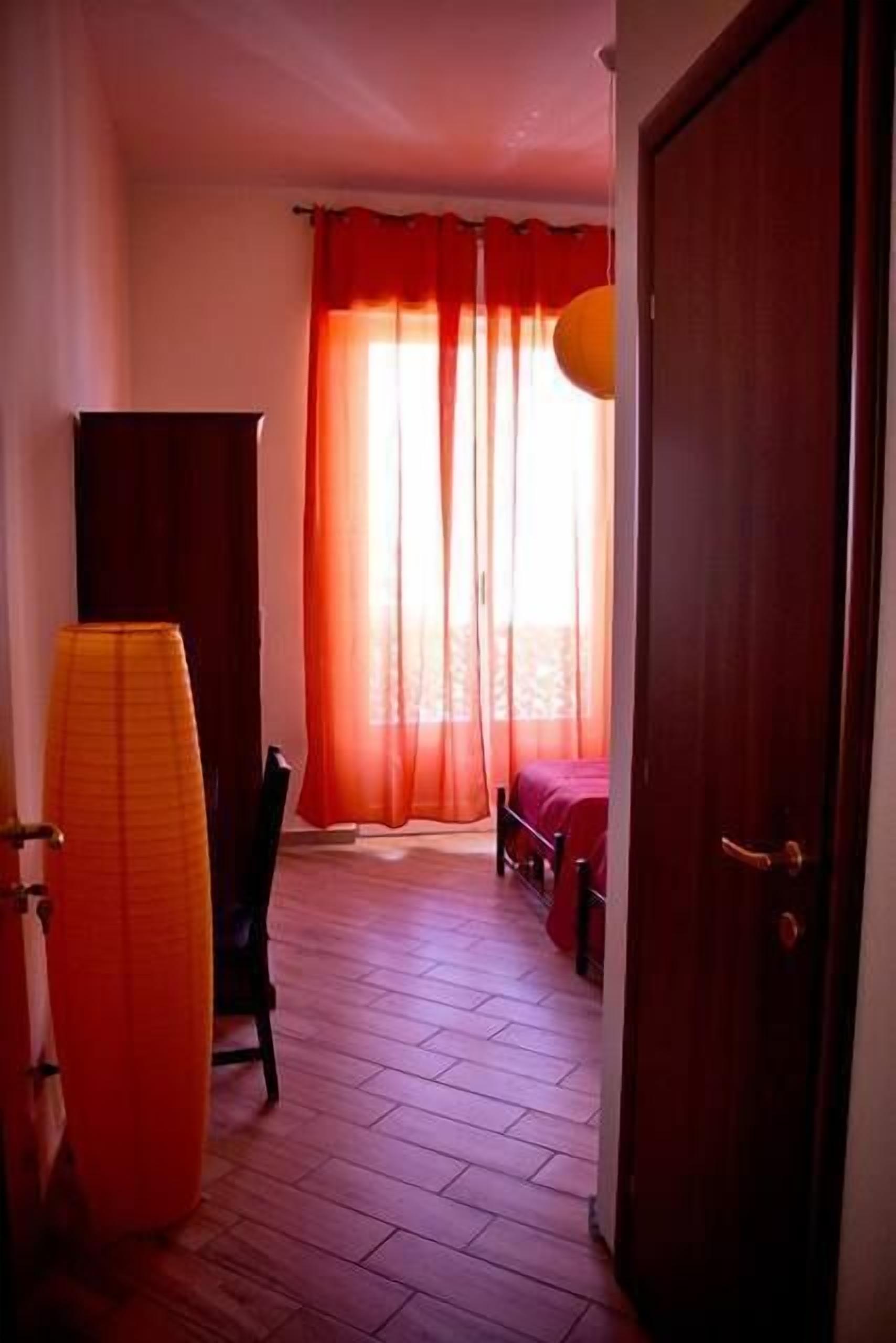 A room with a wooden floor, a bed, a chair, and a door.