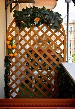 A wooden lattice gate with a decorative arch, featuring green foliage and orange flowers.