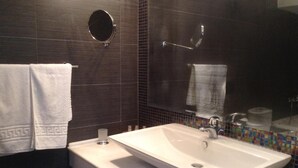 A bathroom with a white sink, dark tiled walls, and a mirror. - Park (Volos)