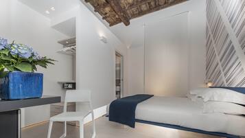 A modern bedroom with a bed, a desk, a chair, and a potted plant.
