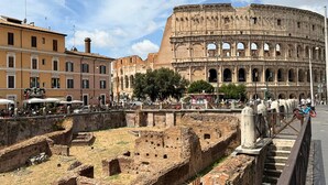 The Colosseum with surrounding ancient ruins and modern buildings. - First Floor (Rome)